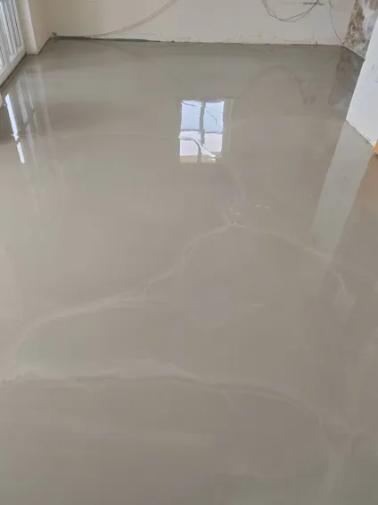 Sveže vlita izravnalna masa na tleh pred polaganjem parketa.